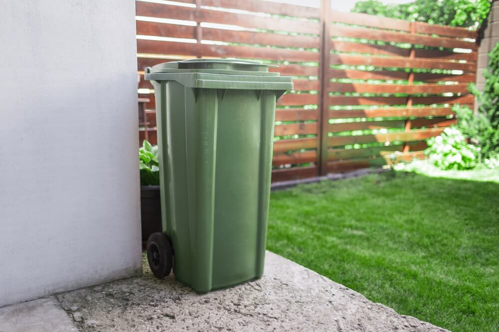 Plastikowy pojemnik na śmieci obok domu
